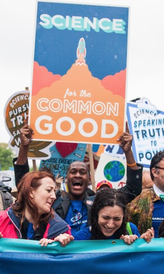 Me on holding a sign that reads “Science for the common good”